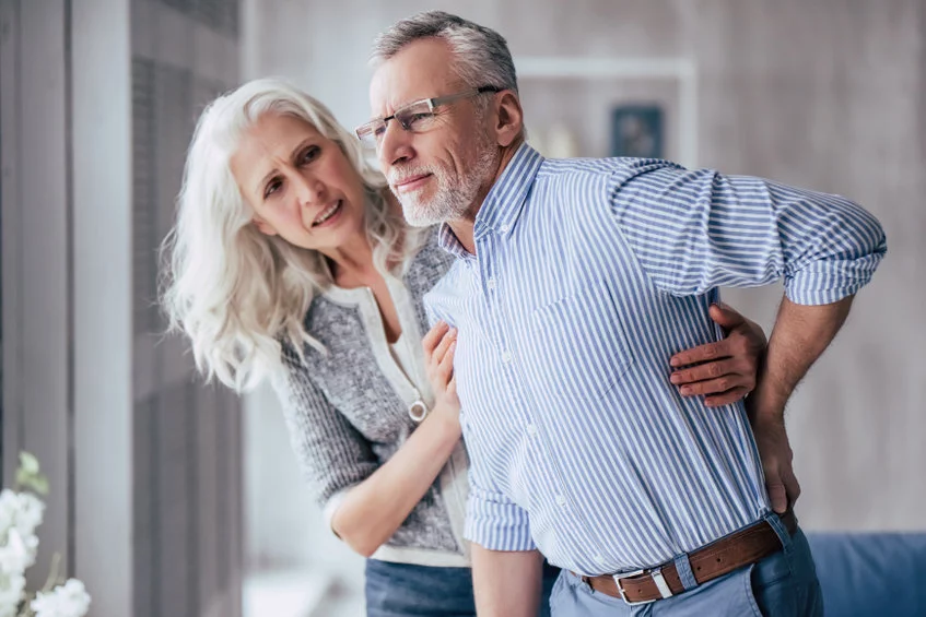 Young lady providing support to old man having Lower back pain