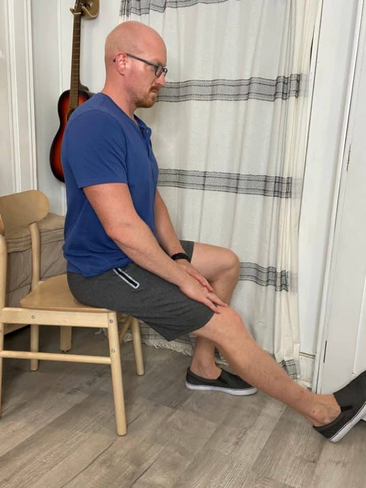 Coach Todd performing seated hamstring stretch to relieve lower back discomfort from sitting through increased leg muscle flexibility