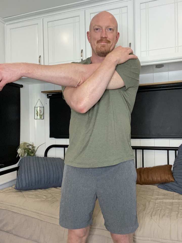 Coach Todd demonstrating cross-arm stretch as a component of the standing hip flexor stretch routine to enhance shoulder flexibility and reduce muscle tightness