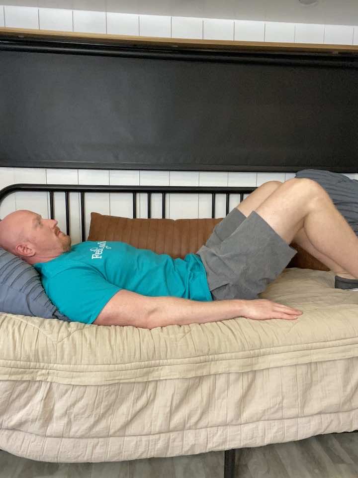 Knee Pain Specialist and Injury Prevention Expert, Coach Todd, lying on his back with knees bent and hands on his stomach, demonstrating Lumbar Stabilization Exercises called abdominal bracing