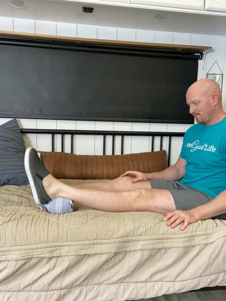 Coach Todd executing Heel Prop, a therapeutic exercise for those dealing with a Patellar Tendon Tear, aimed at improving knee extension and promoting healing