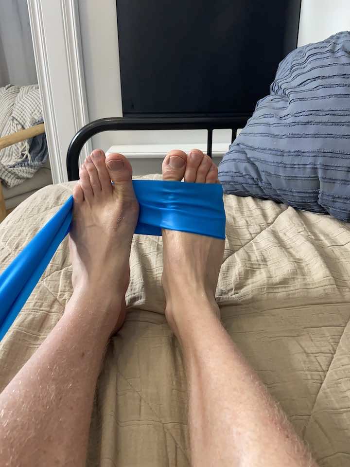 Performing ankle dorsiflexion with a resistance band, a helpful exercise for strengthening ankle muscles and reducing heel pain.