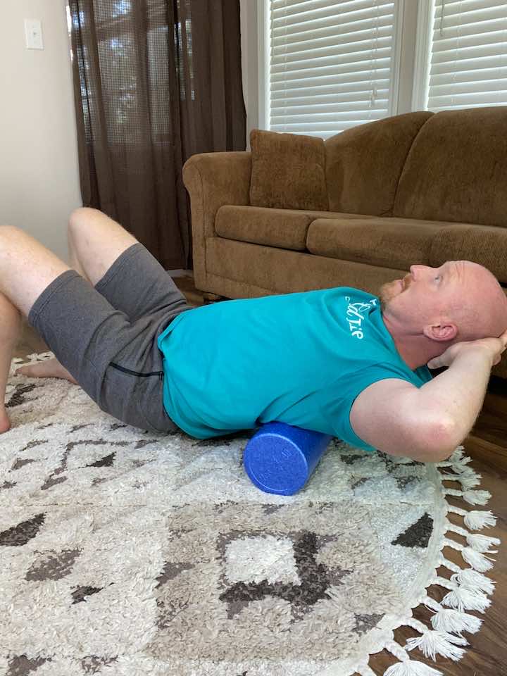 Using a foam roller for a back extension, aiding in reducing lower back stiffness.